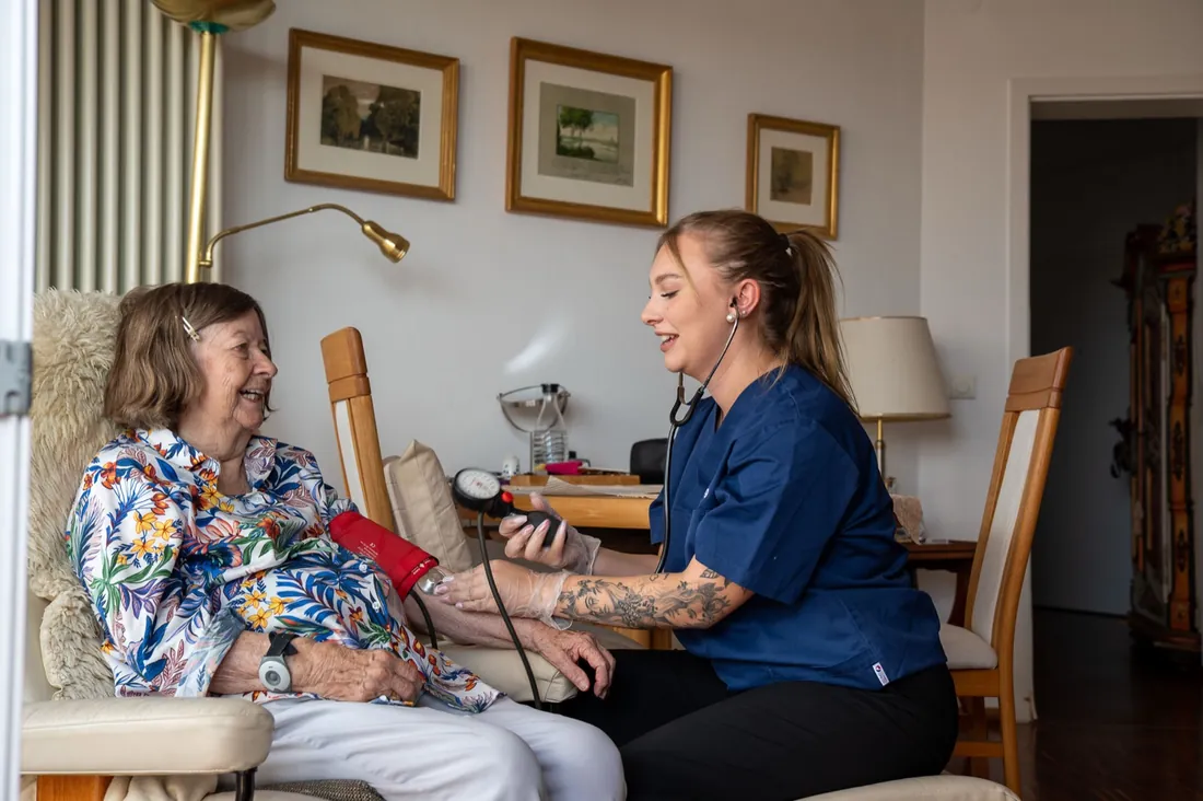 Pflegekraft der Pflegedienst Zwilling GmbH misst Blutdruck bei einer Patientin zu Hause
